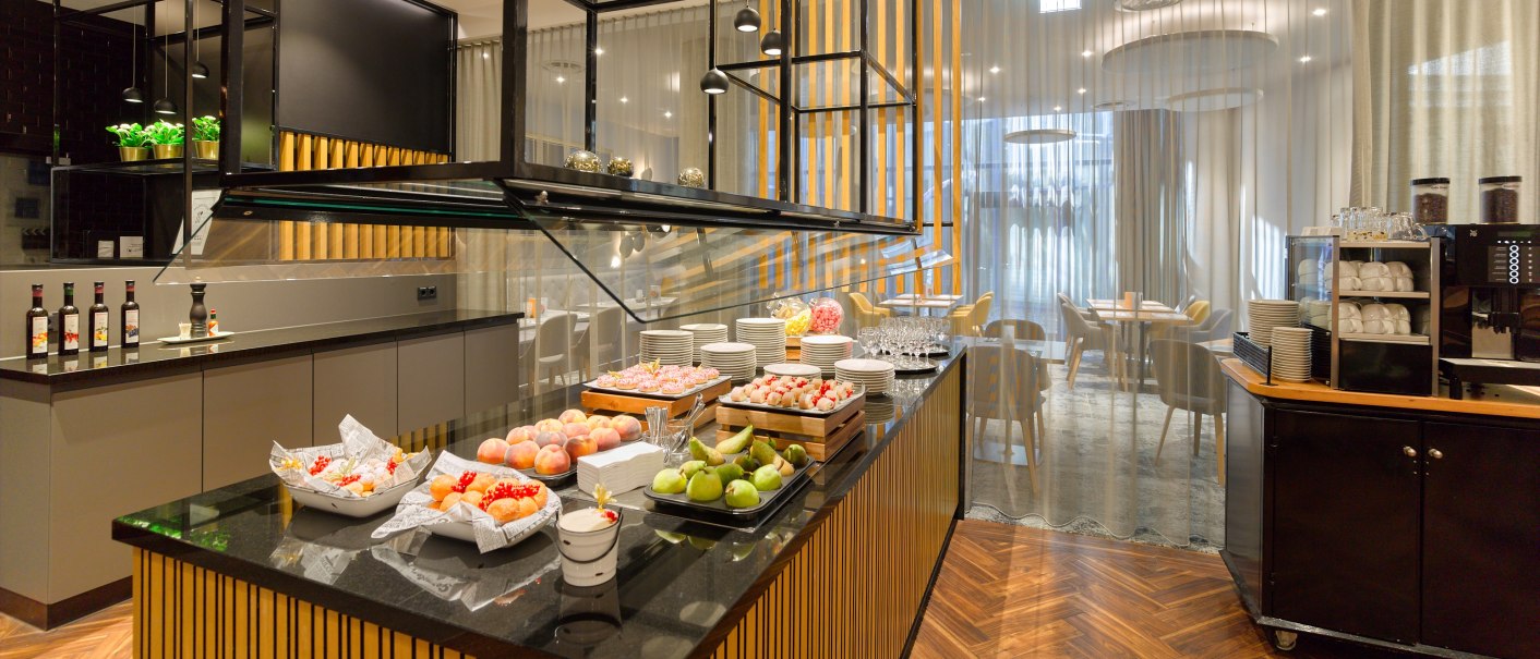 Elegantes Buffet mit Obst und Getränken in einem modernen Restaurant mit Holzboden und stilvoller Einrichtung., © Holiday Inn Stuttgart Elegantes Buffet mit Obst und Getränken in einem modernen Restaurant mit Holzboden und stilvoller Einrichtung., © Holiday Inn Stuttgart