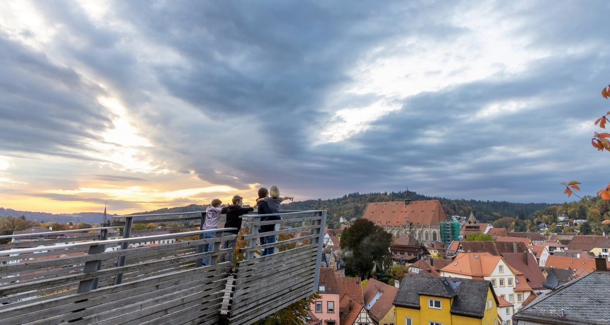 Auf der aus Holz verkleideten Aussichtsplattform stehen zwei Jungen und eine Frau die ein Mädchen auf dem Arm hat. Der Himmel ist wolkig, aber die Sonne scheint an einzelnen Stellen durch. Der Blick zeigt Schwäbisch Gmünd von oben. Gut erkennbar ist das Heilig-Kreuz-Münster., © Foto: Thomas Zehnder Auf der aus Holz verkleideten Aussichtsplattform stehen zwei Jungen und eine Frau die ein Mädchen auf dem Arm hat. Der Himmel ist wolkig, aber die Sonne scheint an einzelnen Stellen durch. Der Blick zeigt Schwäbisch Gmünd von oben. Gut erkennbar ist das Heilig-Kreuz-Münster., © Foto: Thomas Zehnder