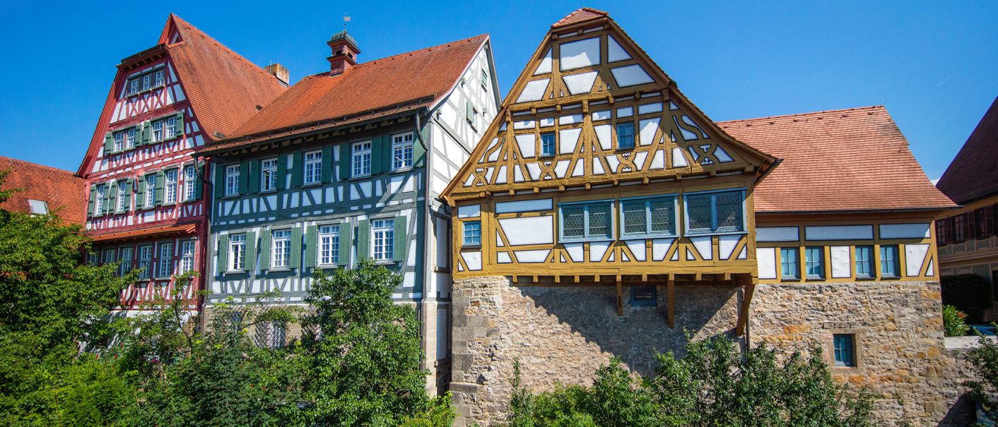 Fachwerkhäuser mit roten Dächern und grünen Fensterläden, umgeben von Bäumen, unter klarem blauem Himmel., © Stuttgart-Marketing GmbH, Achim Mende Fachwerkhäuser mit roten Dächern und grünen Fensterläden, umgeben von Bäumen, unter klarem blauem Himmel., © Stuttgart-Marketing GmbH, Achim Mende