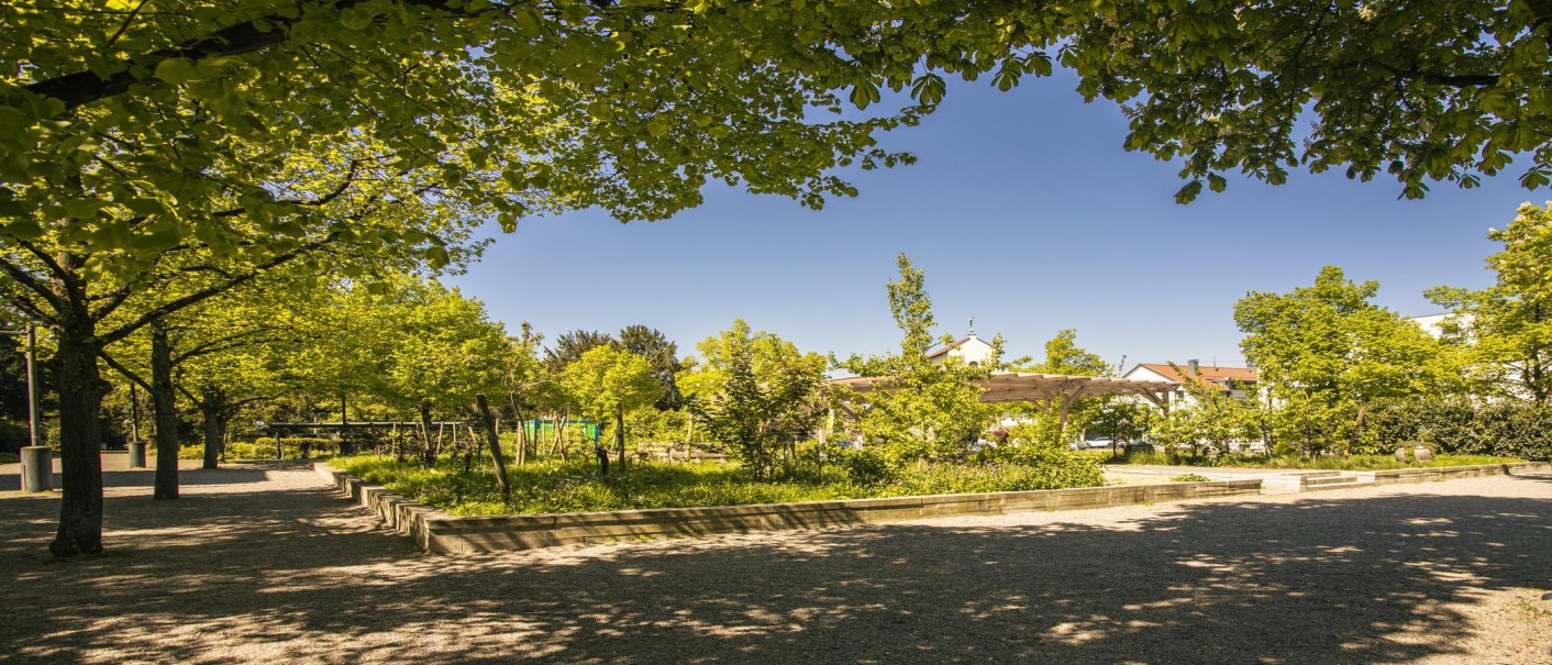 Ein grüner Park in Fellbach mit Bäumen, einem Spielplatz und einem Pavillon unter blauem Himmel., © SMG, Sarah Schmid