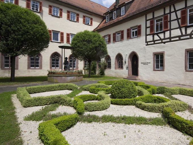 Ein gepflegter Garten mit kunstvollen Heckenmustern vor einem historischen Geb&auml;ude mit Fachwerk und roten Fensterl&auml;den., &copy; Stadtverwaltung Weil der Stadt