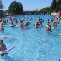 Viele Menschen genießen einen sonnigen Tag im Freibad Renningen. Kinder und Erwachsene schwimmen und spielen im Wasser., © Stadt Renningen