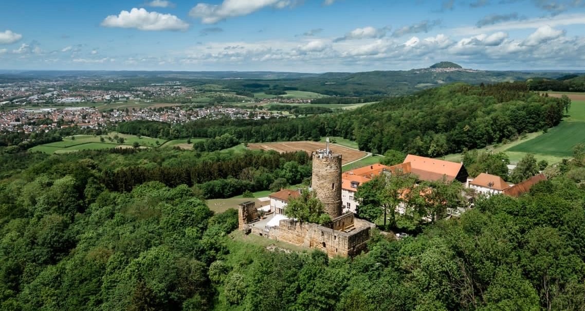 Luftaufnahme der Burg Staufeneck, umgeben von grüner Landschaft und Wäldern, mit Blick auf eine Stadt im Hintergrund., © Christian Prerauer Luftaufnahme der Burg Staufeneck, umgeben von grüner Landschaft und Wäldern, mit Blick auf eine Stadt im Hintergrund., © Christian Prerauer