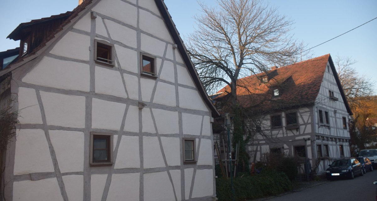 Zwei Fachwerkhäuser in einer ländlichen Straße, umgeben von kahlen Bäumen und parkenden Autos., © Land der 1000 Hügel - Kraichgau-Stromberg Zwei Fachwerkhäuser in einer ländlichen Straße, umgeben von kahlen Bäumen und parkenden Autos., © Land der 1000 Hügel - Kraichgau-Stromberg