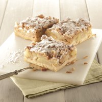Drei Apfelschnitten mit Streuseln und Puderzucker auf einem weißen Brett, daneben ein Messer auf einem grünen Tuch., © Bäckerei Veit, Victoria Huber Drei Apfelschnitten mit Streuseln und Puderzucker auf einem weißen Brett, daneben ein Messer auf einem grünen Tuch., © Bäckerei Veit, Victoria Huber