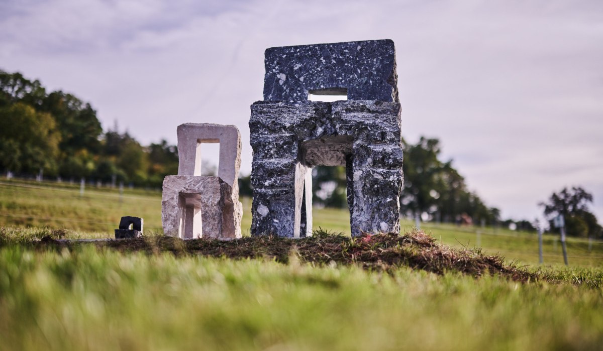 Kleine Steinskulpturen stehen auf einer Wiese. Der Himmel ist bew&ouml;lkt, und im Hintergrund sind B&auml;ume zu sehen., &copy; Natur.Nah. Sch&ouml;nbuch & Heckeng&auml;u