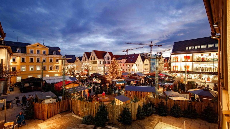 Abendlicher Weihnachtsmarkt in Göppingen mit festlich beleuchteten Ständen und einem großen Weihnachtsbaum, umgeben von historischen Gebäuden., © Stadt Göppingen