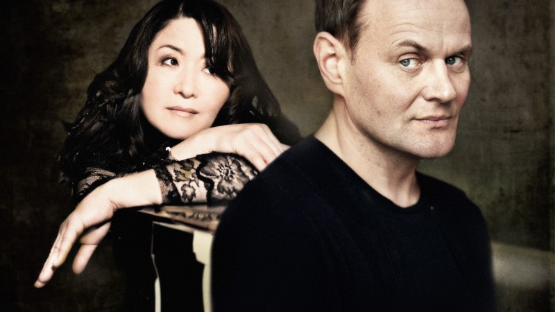 Eine Frau lehnt sich auf einen Tisch, w&auml;hrend ein Mann im Vordergrund steht. Beide blicken in unterschiedliche Richtungen, vor einem dunklen Hintergrund., &copy; Arens Schult