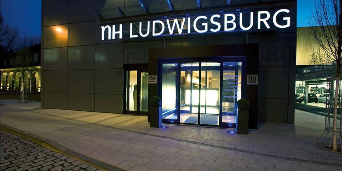 Eingang des NH Hotels in Ludwigsburg bei Nacht, beleuchtet mit blauem Licht. Der Schriftzug 'NH LUDWIGSBURG' ist gut sichtbar., © NH Ludwigsburg