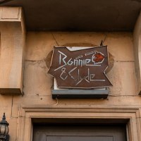 Ein Schild mit der Aufschrift 'Bonnie & Clyde' hängt an einem Gebäude. Die Fassade ist aus Stein, und es gibt dekorative Laternen., © SMG. Sarah Schmid Ein Schild mit der Aufschrift 'Bonnie & Clyde' hängt an einem Gebäude. Die Fassade ist aus Stein, und es gibt dekorative Laternen., © SMG. Sarah Schmid