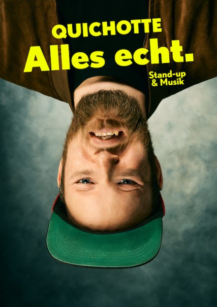 Ein Mann mit Bart und grüner Kappe steht auf dem Kopf. Text: 'Quichotte Alles echt. Stand-up & Musik'., © Scala Kultur Live gGmbH