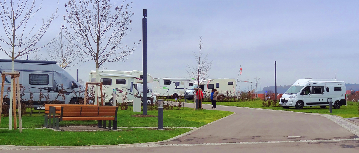 Wohnmobilstellplatz mit mehreren Wohnmobilen, kahlen Bäumen und einer Bank. Zwei Personen stehen auf dem Weg. Trübes Wetter., © Panorama Therme Beuren, Birgit Eschment Wohnmobilstellplatz mit mehreren Wohnmobilen, kahlen Bäumen und einer Bank. Zwei Personen stehen auf dem Weg. Trübes Wetter., © Panorama Therme Beuren, Birgit Eschment
