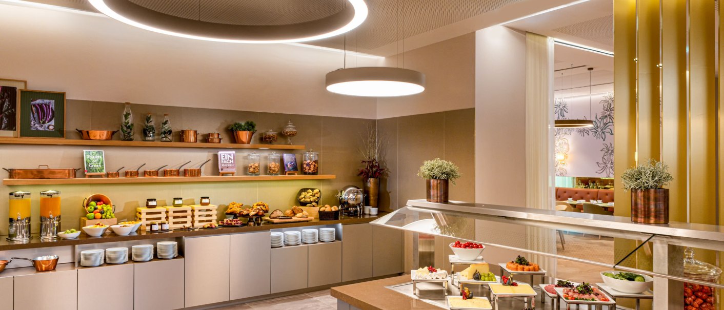 Ein stilvolles Frühstücksbuffet mit Obst, Gebäck, Aufschnitt und Getränken in einem modernen Raum mit eleganter Beleuchtung., © Mövenpick Hotel Stuttgart Messe & Congress Ein stilvolles Frühstücksbuffet mit Obst, Gebäck, Aufschnitt und Getränken in einem modernen Raum mit eleganter Beleuchtung., © Mövenpick Hotel Stuttgart Messe & Congress