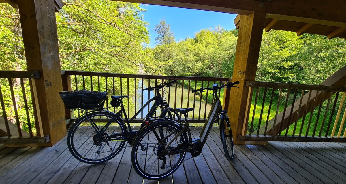 Zwei Fahrr&auml;der auf einer Holzbr&uuml;cke &uuml;ber einem Fluss, umgeben von &uuml;ppigem Gr&uuml;n und strahlend blauem Himmel., &copy; N&ouml;rdlicher Schwarzwald