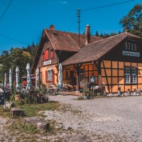 Fachwerkgebäude 'Laufenmühle' mit Sonnenschirmen und Außenbereich, umgeben von Wald, unter blauem Himmel., © Stadt Welzheim Fachwerkgebäude 'Laufenmühle' mit Sonnenschirmen und Außenbereich, umgeben von Wald, unter blauem Himmel., © Stadt Welzheim
