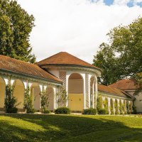 Die Wandelhalle in Bad Boll zeigt elegante Arkaden und ein rotes Ziegeldach, eingebettet in eine grüne Landschaft mit Bäumen und Rasen., © SMG, Sarah Schmid Die Wandelhalle in Bad Boll zeigt elegante Arkaden und ein rotes Ziegeldach, eingebettet in eine grüne Landschaft mit Bäumen und Rasen., © SMG, Sarah Schmid