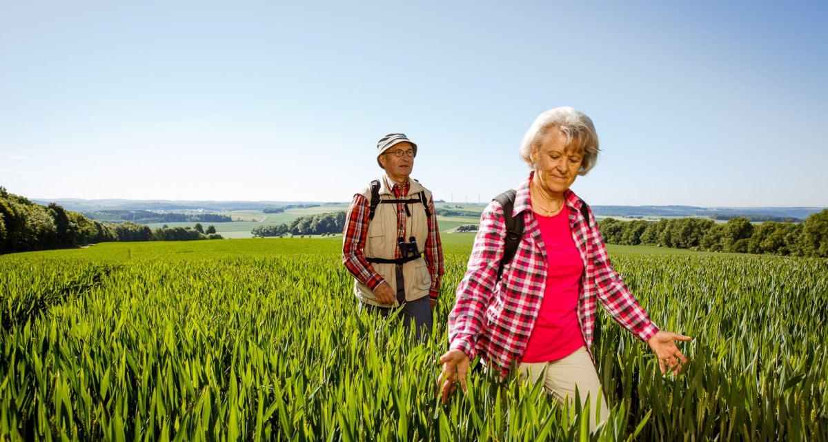 Zwei ältere Personen wandern durch ein grünes Feld. Der Himmel ist klar und blau, die Landschaft weitläufig und grün., © Landkreis Göppingen Zwei ältere Personen wandern durch ein grünes Feld. Der Himmel ist klar und blau, die Landschaft weitläufig und grün., © Landkreis Göppingen
