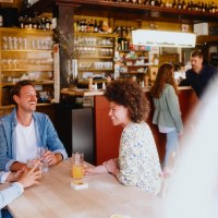 Drei Personen sitzen lachend an einem Tisch in einer gemütlichen Bar. Im Hintergrund sind Gläser und Flaschen zu sehen., © Stuttgart-Marketing GmbH, Alwin Maigler Drei Personen sitzen lachend an einem Tisch in einer gemütlichen Bar. Im Hintergrund sind Gläser und Flaschen zu sehen., © Stuttgart-Marketing GmbH, Alwin Maigler