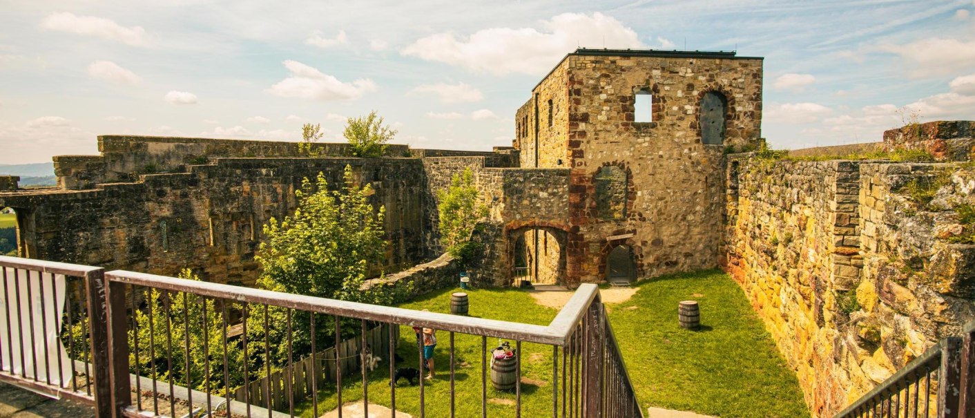 Die Ruinen der Burg Hohenrechberg in Schw&auml;bisch Gm&uuml;nd zeigen alte Steinmauern und einen gr&uuml;nen Innenhof mit B&auml;umen und F&auml;ssern., &copy; Stuttgart-Marketing GmbH, Sarah Schmid