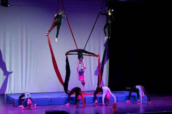 Kinder zeigen Akrobatik auf einer Bühne mit Tüchern und Matten. Einige hängen an Tüchern, andere machen Bodenübungen. Die Bühne ist bunt beleuchtet., © Kunstschule Labyrinth Kinder zeigen Akrobatik auf einer Bühne mit Tüchern und Matten. Einige hängen an Tüchern, andere machen Bodenübungen. Die Bühne ist bunt beleuchtet., © Kunstschule Labyrinth