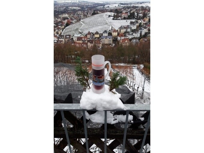 Ein Gl&uuml;hweinbecher auf einem verschneiten Gel&auml;nder, im Hintergrund eine winterliche Stadtlandschaft mit Weinbergen., &copy; Weingenuss Stuttgart
