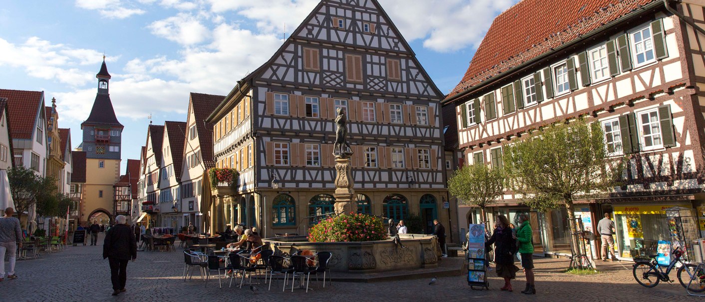 Marktplatz in Winnenden mit Fachwerkhäusern, einem zentralen Brunnen und Menschen, die den Platz beleben. Im Hintergrund ein Turm mit Uhr., © Stuttgart-Marketing GmbH Marktplatz in Winnenden mit Fachwerkhäusern, einem zentralen Brunnen und Menschen, die den Platz beleben. Im Hintergrund ein Turm mit Uhr., © Stuttgart-Marketing GmbH