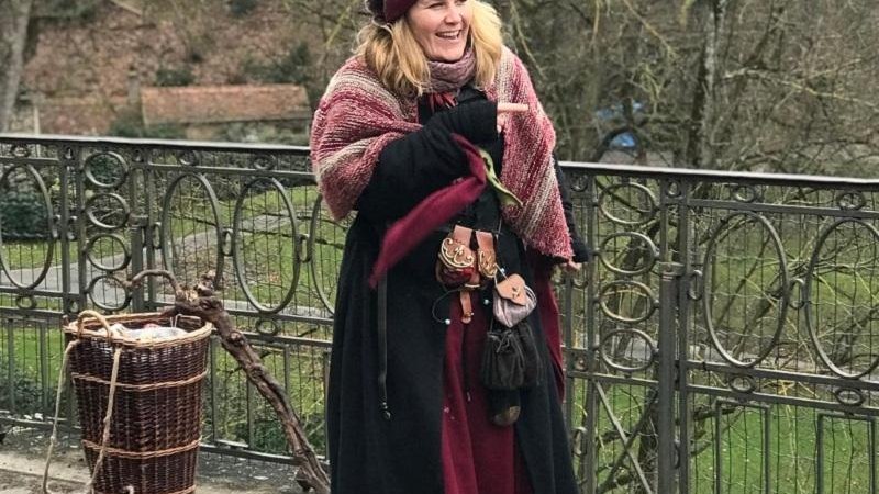 Eine Frau in mittelalterlicher Kleidung steht auf einer Br&uuml;cke. Sie tr&auml;gt einen Umhang und hat einen Korb und einen Stock bei sich., &copy; Tourist Information und Ticket Service Ludwigsburg