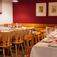 Gemütlich gedeckter Tisch in einem Restaurant mit Weingläsern, Kerzen und Holzmöbeln. Die Wände sind rot und weiß dekoriert., © 70469R! Weinbau Fabian Rajtschan