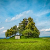 Der Hagbergturm in Gschwend steht auf einem Hügel, umgeben von Bäumen und einer grünen Wiese. Ein kleiner Weg führt zum Turm, der Himmel ist blau mit Wolken., © agentur arcos/Niki Eilers