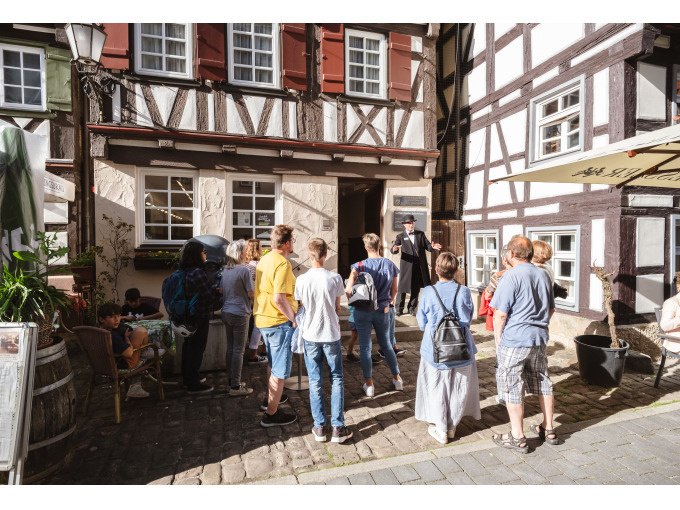 Eine Gruppe von Menschen lauscht einem F&uuml;hrer vor einem historischen Fachwerkhaus. Die Szene spielt sich bei sonnigem Wetter ab., &copy; Eigenbetrieb Tourismus und Citymanagement Schorndorf
