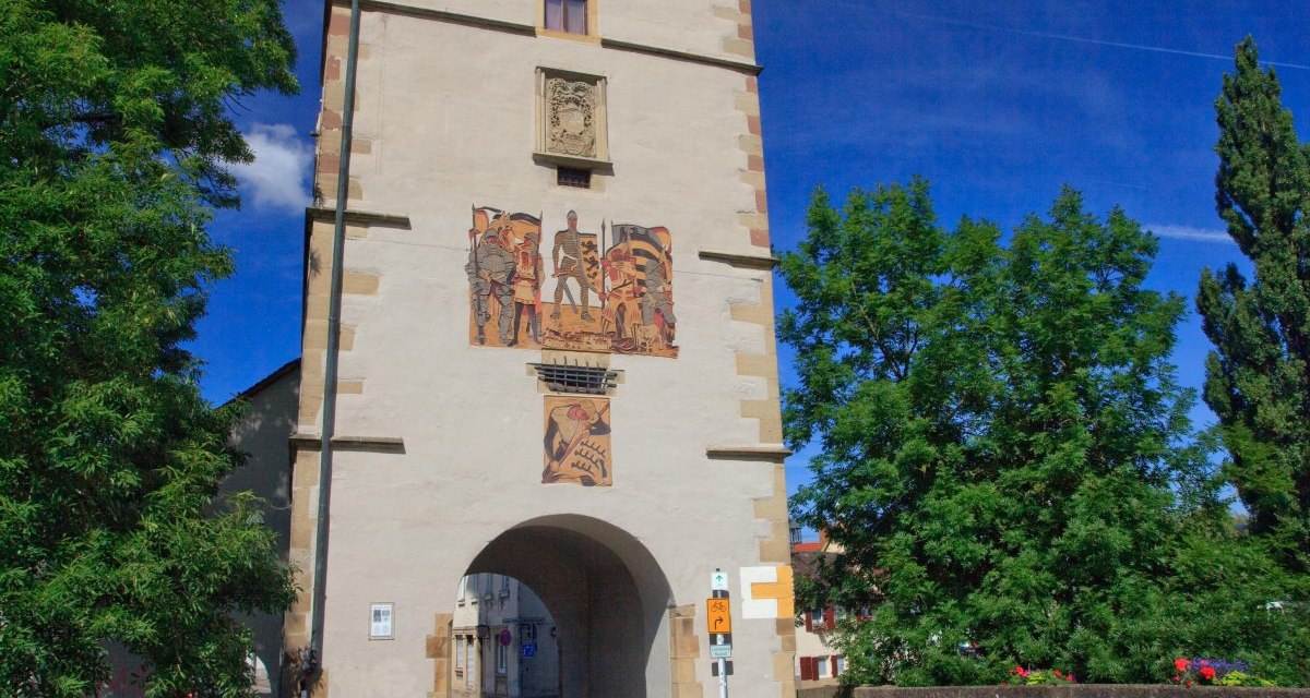 Der Beinsteiner Torturm erhebt sich majestätisch unter einem klaren blauen Himmel. Bunte Blumen schmücken die Brücke im Vordergrund., © Waiblingen - Stuttgart-Marketing GmbH Der Beinsteiner Torturm erhebt sich majestätisch unter einem klaren blauen Himmel. Bunte Blumen schmücken die Brücke im Vordergrund., © Waiblingen - Stuttgart-Marketing GmbH