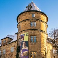 Das Alte Schloss in Stuttgart bei klarem Himmel. Ein Werbebanner schm&uuml;ckt die Fassade. Die Sonne scheint durch die kahlen B&auml;ume., &copy; Stuttgart-Marketing GmbH, Sarah Schmid