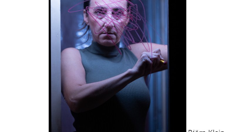 Eine Frau in einem dunklen Raum zeichnet mit einem Stift auf eine Glasscheibe. Die Szene ist in bläulichem Licht gehalten., © Kultur- und Sportamt Stadt Bietigheim-Bissingen Eine Frau in einem dunklen Raum zeichnet mit einem Stift auf eine Glasscheibe. Die Szene ist in bläulichem Licht gehalten., © Kultur- und Sportamt Stadt Bietigheim-Bissingen