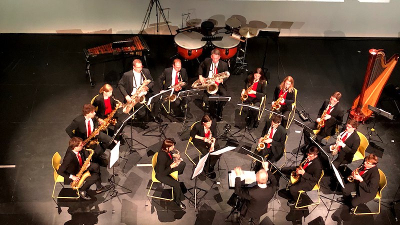 Ein Saxophon-Ensemble spielt auf einer B&uuml;hne, dirigiert von einer Person. Im Hintergrund sind Schlaginstrumente und eine Harfe zu sehen., &copy; Sch&ouml;nblick gemeinn&uuml;tzige GmbH