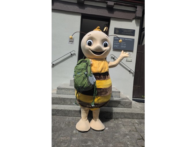 Eine Person im Bienenkost&uuml;m mit gr&uuml;nem Rucksack steht vor einem Geb&auml;ude in Schorndorf., &copy; Eigenbetrieb Tourismus und Citymanagement Schorndorf
