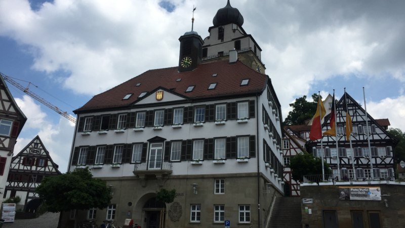 Das Rathaus von Herrenberg mit Fachwerkhäusern im Hintergrund. Vor dem Gebäude stehen leere Stühle. Der Himmel ist bewölkt., © www.pro-cycl.de Das Rathaus von Herrenberg mit Fachwerkhäusern im Hintergrund. Vor dem Gebäude stehen leere Stühle. Der Himmel ist bewölkt., © www.pro-cycl.de