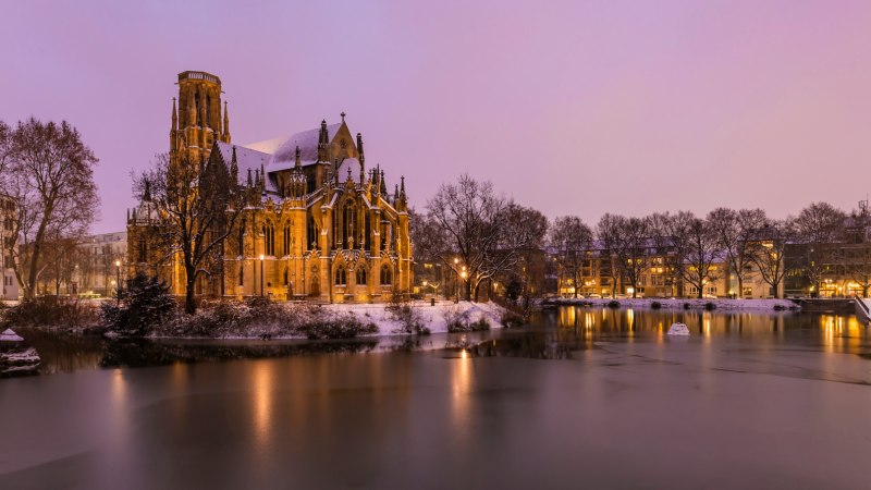 Die Johanneskirche am Feuersee in winterlicher Abendstimmung, umgeben von Schnee und beleuchtetem Wasser., &copy; Werner Dietrich
