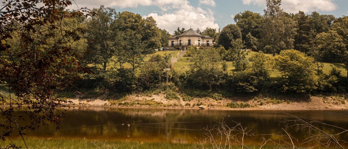 Das Bärenschlössle thront auf einem grünen Hügel am Bärensee, umgeben von üppigen Bäumen und einem klaren Himmel mit weißen Wolken., © SMG, Sarah Schmid