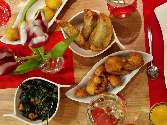 Ein Tisch mit indischen Vorspeisen wie Samosas und frittiertem Gemüse, dekoriert mit Tulpen und Getränken. Einladende Atmosphäre für einen Kochkurs., © Kultweine-Kochwelten-Kunstücke - Kochschule Sonja Lenz Ein Tisch mit indischen Vorspeisen wie Samosas und frittiertem Gemüse, dekoriert mit Tulpen und Getränken. Einladende Atmosphäre für einen Kochkurs., © Kultweine-Kochwelten-Kunstücke - Kochschule Sonja Lenz