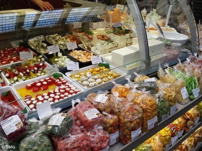 Verkaufsstand in der Stuttgarter Markthalle mit einer Auswahl an Käse, Antipasti und verpackten Snacks in einer Glasvitrine., © Stuttgart Marketing GmbH Verkaufsstand in der Stuttgarter Markthalle mit einer Auswahl an Käse, Antipasti und verpackten Snacks in einer Glasvitrine., © Stuttgart Marketing GmbH