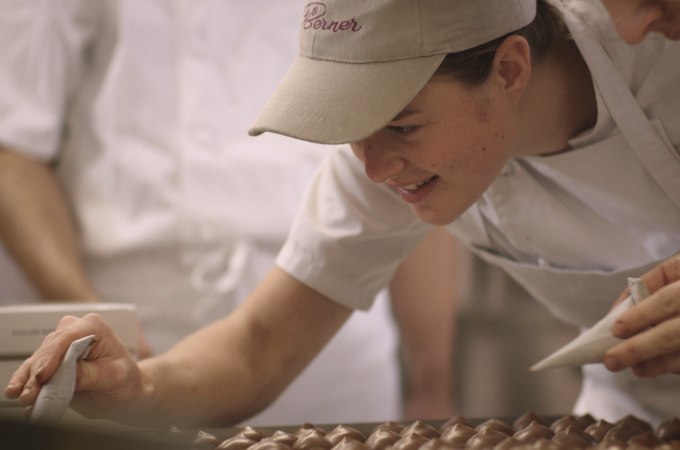 Eine Person in einer B&auml;ckerei verziert Pralinen mit einem Spritzbeutel. Sie tr&auml;gt eine Schirmm&uuml;tze und ein wei&szlig;es T-Shirt., &copy; Stadt G&ouml;ppingen