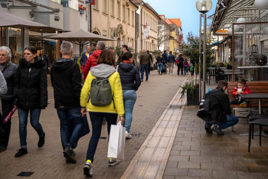 Belebte Einkaufsstra&szlig;e mit Menschen, die spazieren gehen. Gesch&auml;fte und Caf&eacute;s s&auml;umen den Weg. Ein Kind sitzt mit einem Erwachsenen auf einer Bank., &copy; Ludwigsburger Innenstadt e.V. (LUIS)