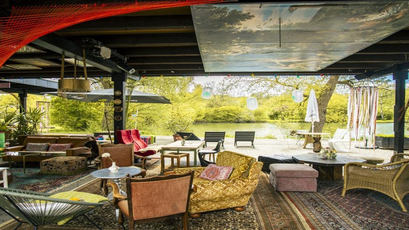 Gemütliche Sitzecke mit bunten Möbeln und Teppichen am Beutwangsee. Blick auf das Wasser und grüne Bäume im Hintergrund., © SMG, Sarah Schmid Gemütliche Sitzecke mit bunten Möbeln und Teppichen am Beutwangsee. Blick auf das Wasser und grüne Bäume im Hintergrund., © SMG, Sarah Schmid