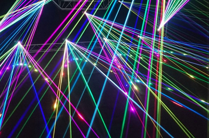 Bunte Laserstrahlen durchziehen einen dunklen Raum und erzeugen ein lebendiges, futuristisches Muster., © Cool-Tours StattReisen