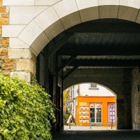 Ein steinerner Torbogen führt zu einem orangefarbenen Gebäude. Links sind grüne Pflanzen, rechts eine Steinmauer., © Stuttgart-Marketing GmbH, Sarah Schmid