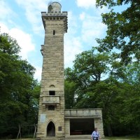 Der Kernenturm erhebt sich steinern inmitten eines Waldes. Eine Person geht im Vordergrund. Der Himmel ist leicht bewölkt., © Ingrid Sachsenmaier