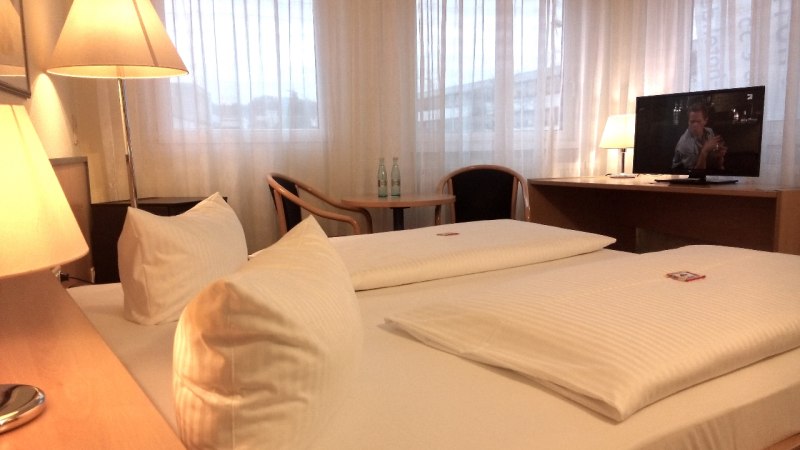 Gemütliches Doppelzimmer mit Doppelbett, Schreibtisch, Stuhl und Fernseher. Große Fenster mit Vorhängen., © Central Hotel