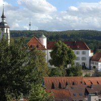 Ein Schloss mit rotem Dach und Kirchturm, umgeben von Bäumen und Hügeln. Im Hintergrund ist ein Fernsehturm zu sehen., © Natur.Nah. Schönbuch & Heckengäu