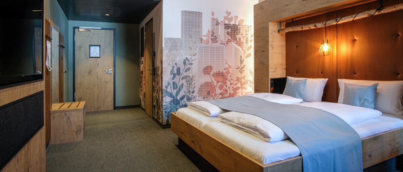Modernes Hotelzimmer mit Doppelbett, dekorativer Wandkunst und Holzdetails. Eine warme Beleuchtung schafft eine gemütliche Atmosphäre., © 13 6 Design GmbH (Judenhof 10, 89073 Ulm) Modernes Hotelzimmer mit Doppelbett, dekorativer Wandkunst und Holzdetails. Eine warme Beleuchtung schafft eine gemütliche Atmosphäre., © 13 6 Design GmbH (Judenhof 10, 89073 Ulm)