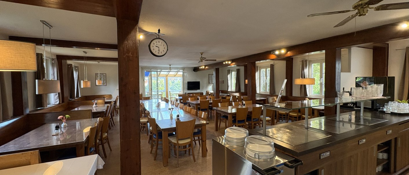 Ein gem&uuml;tliches Restaurant mit Holzm&ouml;beln, gedeckten Tischen und einer gro&szlig;en Uhr an der Decke. Gro&szlig;e Fenster lassen viel Licht herein., &copy; TOMAS